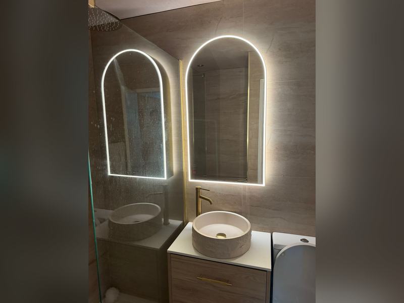 Bathroom with illuminated arched LED mirrors and twin basins