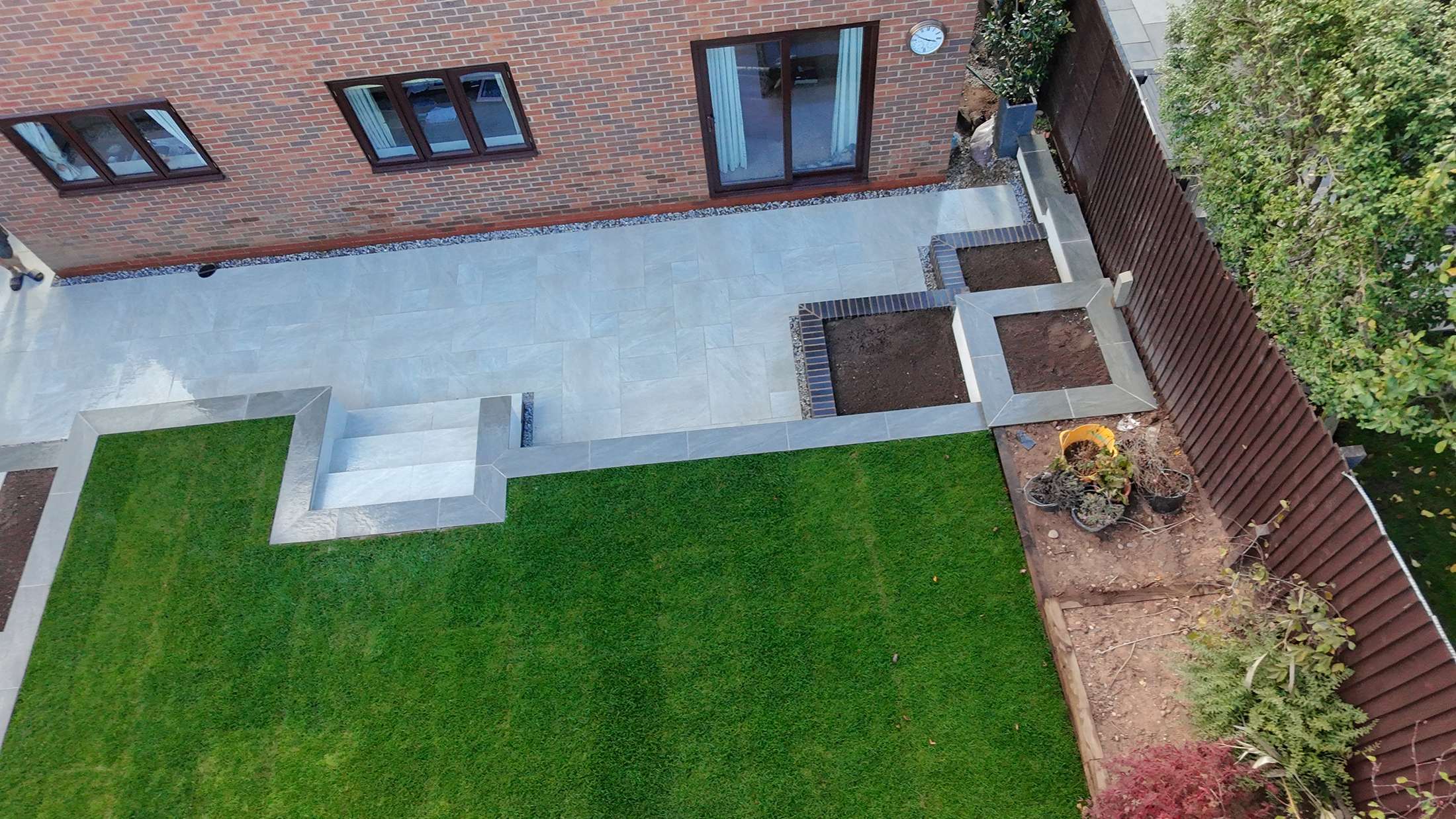 Split-level porcelain patio, steps and lawn built by Trio Construction Group in Bromsgrove
